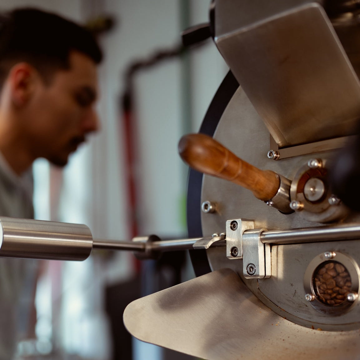 Person operating a coffee roasting machine with a blurred background